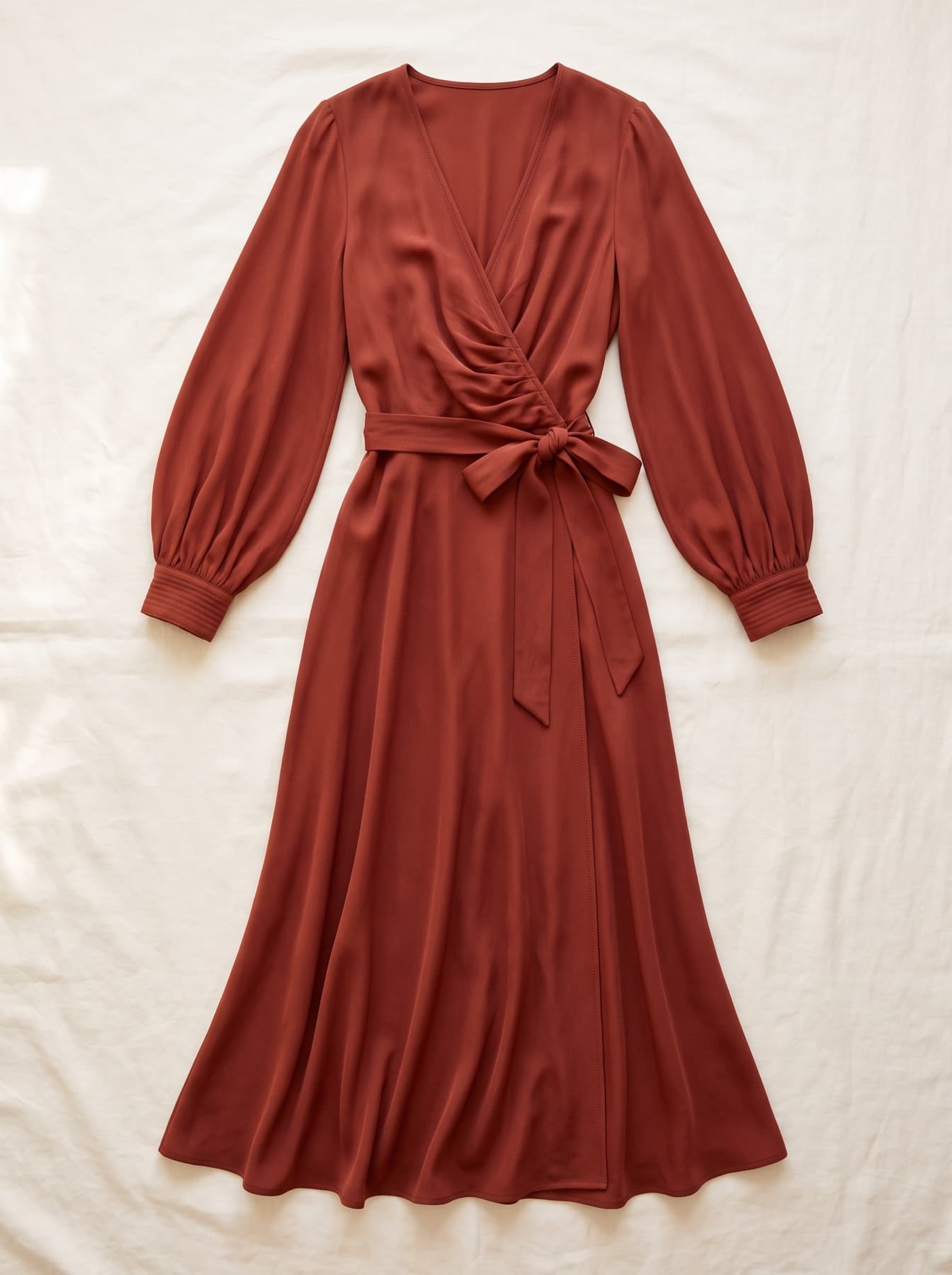 A terracotta silk wrap dress photographed flat, before generation